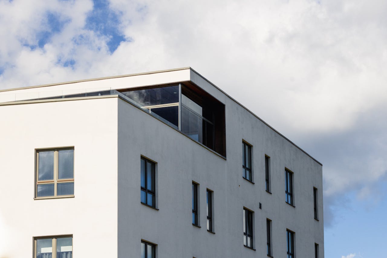 Minimalist white residential building under a partly cloudy sky in Tartu, Estonia.